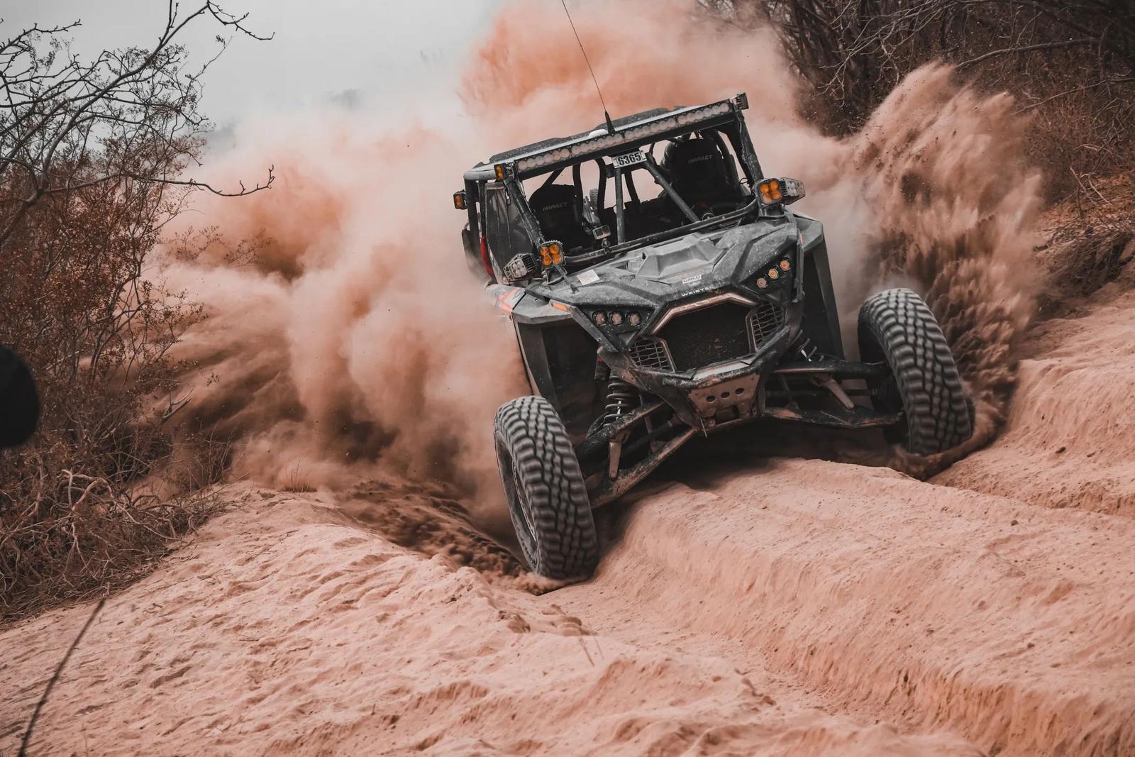 Podium race UTV kicking up dust through a desert sand wash